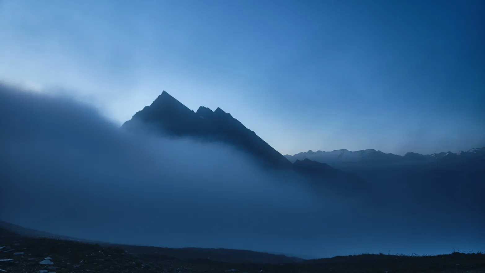 špička hory vykukující z mlhy