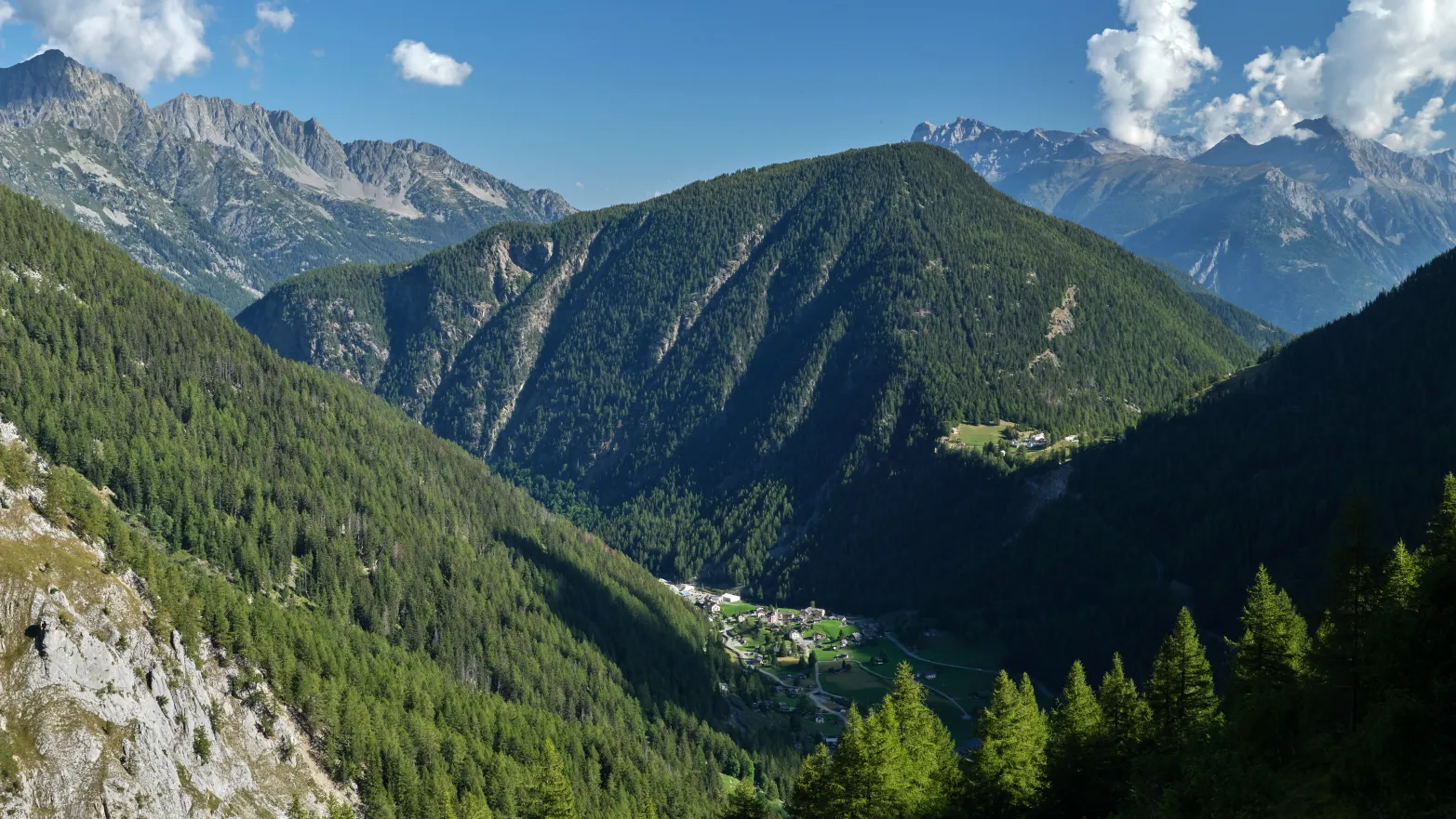 zalesněné horské hřebeny s pár domky v údolí mezi nimi
